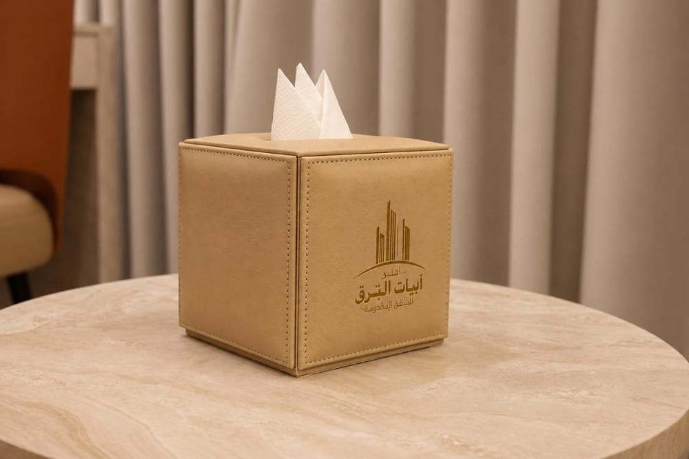 غرفة ديلوكس كينغ: علبة مناديل جلدية ذهبية بشعار الفندق على طاولة رخامية